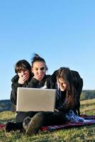 group of teens working on laptop outdoor photo