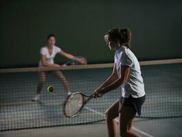 young girls playing tennis game indoor photo