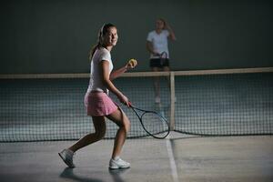 young girls playing tennis game indoor photo