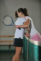 young girls playing tennis game indoor photo