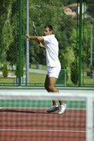 joven hombre jugar tenis al aire librejoven hombre jugar tenis al aire libre foto