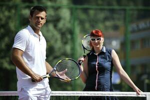 happy young couple play tennis game outdoor photo