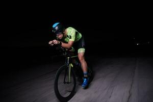 atleta de triatlón montando bicicleta rápido por la noche foto