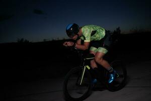 triathlon athlete riding bike fast  at night photo