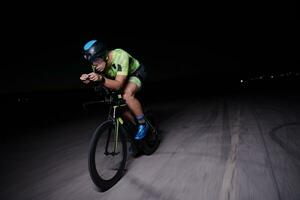 triathlon athlete riding bike fast  at night photo