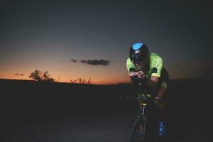 triathlon athlete riding bike fast  at night photo