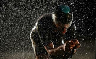 triathlon athlete riding bike  fast on rainy night photo