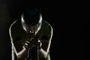 atleta de triatlón montando bicicleta rápido por la noche foto