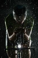 triathlon athlete riding bike  fast on rainy night photo