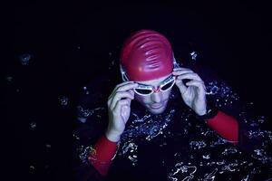 nadador triatleta auténtico que tiene un descanso durante el entrenamiento duro en la noche foto