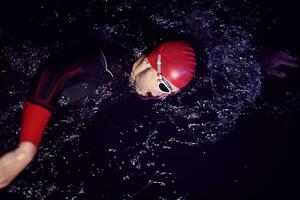 real triathlon athlete swimming in dark night photo