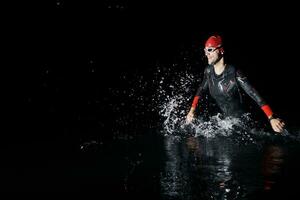 triathlon athlete finishing swimming training at dark night photo