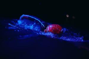 atleta de triatlón real nadando en la noche oscura foto