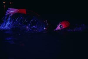 real triathlon athlete swimming in dark night photo