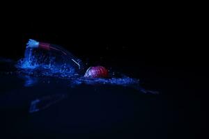 atleta de triatlón real nadando en la noche oscura foto