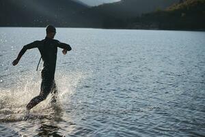 triathlon athlete starting swimming training on lake photo