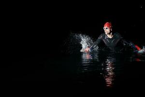 triatlón atleta refinamiento nadando formación a oscuro noche foto