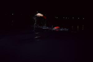 triathlon athlete swimming in dark night  wearing wetsuit photo