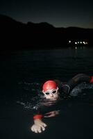 triathlon athlete swimming in dark night  wearing wetsuit photo