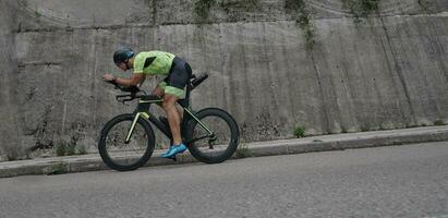 atleta de triatlón montando en bicicleta en el entrenamiento matutino foto