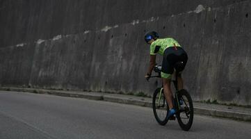 atleta de triatlón montando en bicicleta en el entrenamiento matutino foto