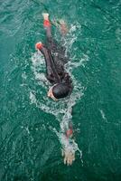 triathlon athlete swimming on lake wearing wetsuit photo