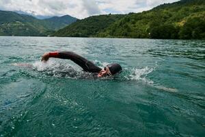 triathlon athlete swimming on lake wearing wetsuit photo