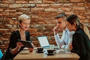 Happy businesspeople smiling cheerfully during a meeting in a coffee shop. Group of successful business professionals working as a team in a multicultural workplace. photo