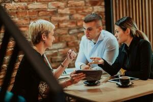 Happy businesspeople smiling cheerfully during a meeting in a coffee shop. Group of successful business professionals working as a team in a multicultural workplace. photo