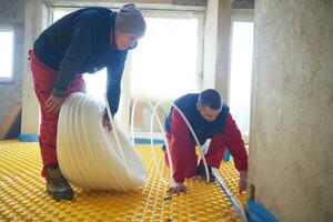 workers installing underfloor heating system photo