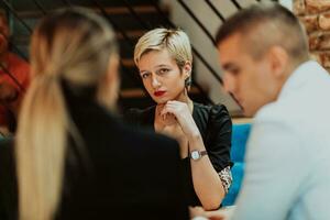 Happy businesspeople smiling cheerfully during a meeting in a coffee shop. Group of successful business professionals working as a team in a multicultural workplace. photo