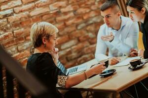 Happy businesspeople smiling cheerfully during a meeting in a coffee shop. Group of successful business professionals working as a team in a multicultural workplace. photo