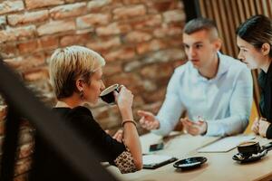 Happy businesspeople smiling cheerfully during a meeting in a coffee shop. Group of successful business professionals working as a team in a multicultural workplace. photo