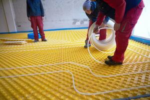 workers installing underfloor heating system photo