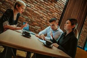 Happy businesspeople smiling cheerfully during a meeting in a coffee shop. Group of successful business professionals working as a team in a multicultural workplace. photo