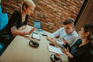 Happy businesspeople smiling cheerfully during a meeting in a coffee shop. Group of successful business professionals working as a team in a multicultural workplace. photo