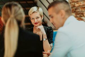 Happy businesspeople smiling cheerfully during a meeting in a coffee shop. Group of successful business professionals working as a team in a multicultural workplace. photo