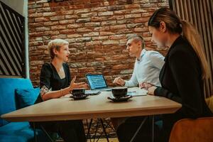 Happy businesspeople smiling cheerfully during a meeting in a coffee shop. Group of successful business professionals working as a team in a multicultural workplace. photo