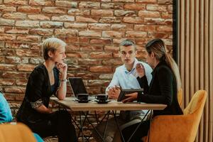 Happy businesspeople smiling cheerfully during a meeting in a coffee shop. Group of successful business professionals working as a team in a multicultural workplace. photo