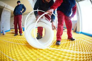 workers installing underfloor heating system photo