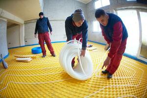 workers installing underfloor heating system photo