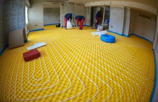 workers installing underfloor heating system photo