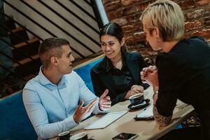 contento gente de negocios sonriente alegremente durante un reunión en un café tienda. grupo de exitoso negocio profesionales trabajando como un equipo en un multicultural lugar de trabajo. foto