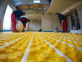 workers installing underfloor heating system photo