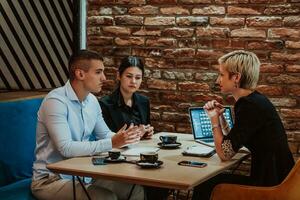 Happy businesspeople smiling cheerfully during a meeting in a coffee shop. Group of successful business professionals working as a team in a multicultural workplace. photo