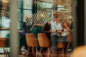 contento gente de negocios sonriente alegremente durante un reunión en un café tienda. grupo de exitoso negocio profesionales trabajando como un equipo en un multicultural lugar de trabajo. foto