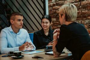 Happy businesspeople smiling cheerfully during a meeting in a coffee shop. Group of successful business professionals working as a team in a multicultural workplace. photo