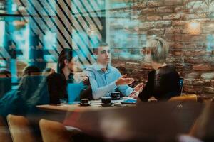 contento gente de negocios sonriente alegremente durante un reunión en un café tienda. grupo de exitoso negocio profesionales trabajando como un equipo en un multicultural lugar de trabajo. foto