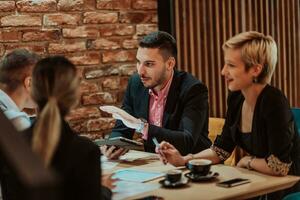 Happy businesspeople smiling cheerfully during a meeting in a coffee shop. Group of successful business professionals working as a team in a multicultural workplace. photo