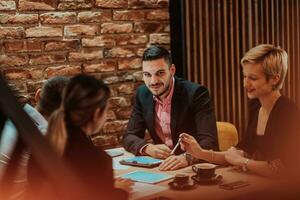 Happy businesspeople smiling cheerfully during a meeting in a coffee shop. Group of successful business professionals working as a team in a multicultural workplace. photo